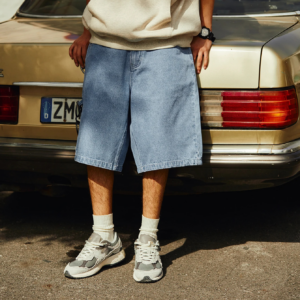 Short Baggy de Style Vintage pour Homme avec un t-shirt beige et des baskets devant une voiture