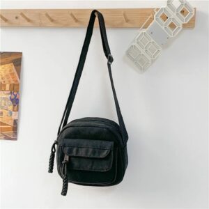 Besace Femme Décontractée Noire accrochée à un porte-manteau avec fond blanc