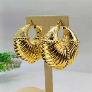 Boucles d'Oreille Africaine Brillantes en Forme de Coquillage installées sur un porte-bijou sur fond gris