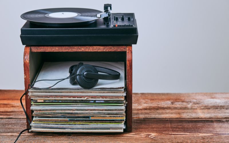 Étagère carrée avec des disques 45 tours, un tourne-disque et un casque audio posé sur une table.