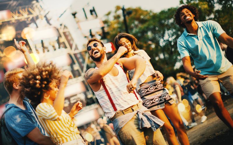 Groupe de personnes en cercle à un festival, qui dansent, rigoles et chantent.